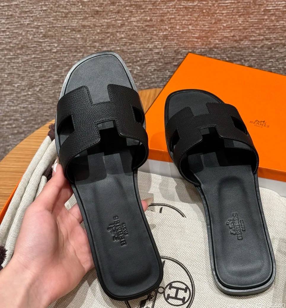 Spot Hermes leather H black flat slippers with matching black stitching – elegant women’s sandals.