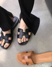 Spot Hermes leather H black flat slippers with matching black stitching – elegant women’s sandals.
