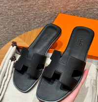 Spot Hermes leather H black flat slippers with matching black stitching – elegant women’s sandals.
