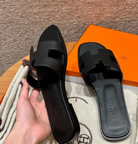 Spot Hermes leather H black flat slippers with matching black stitching – elegant women’s sandals.
