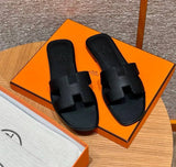 Spot Hermes leather H black flat slippers with matching black stitching – elegant women’s sandals.