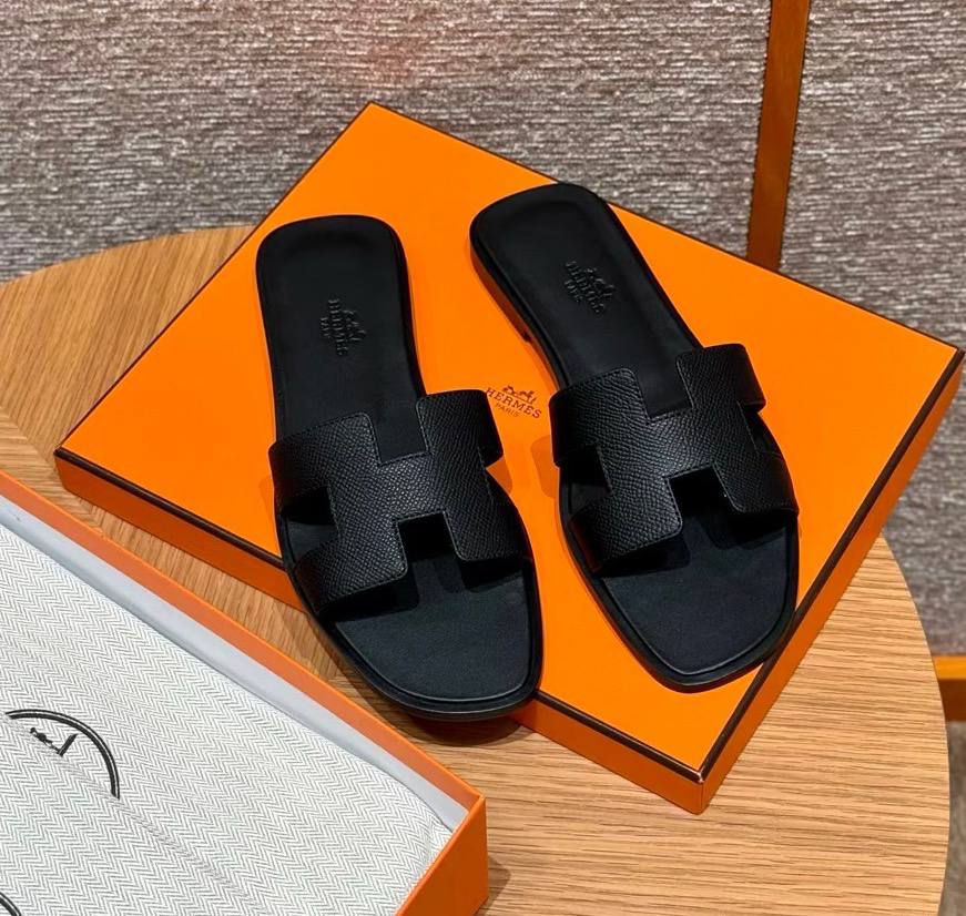 Spot Hermes leather H black flat slippers with matching black stitching – elegant women’s sandals.